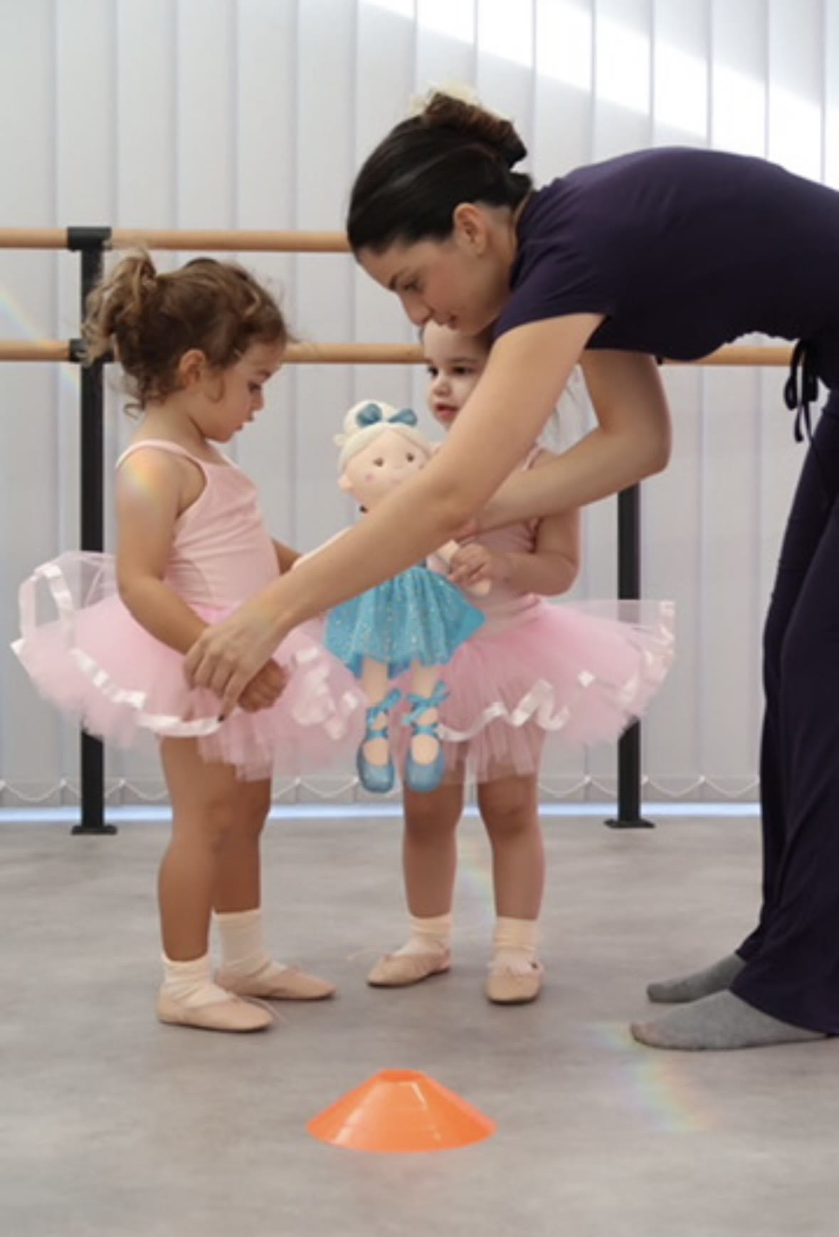Toddlers in pink tutus learning with a ballerina doll